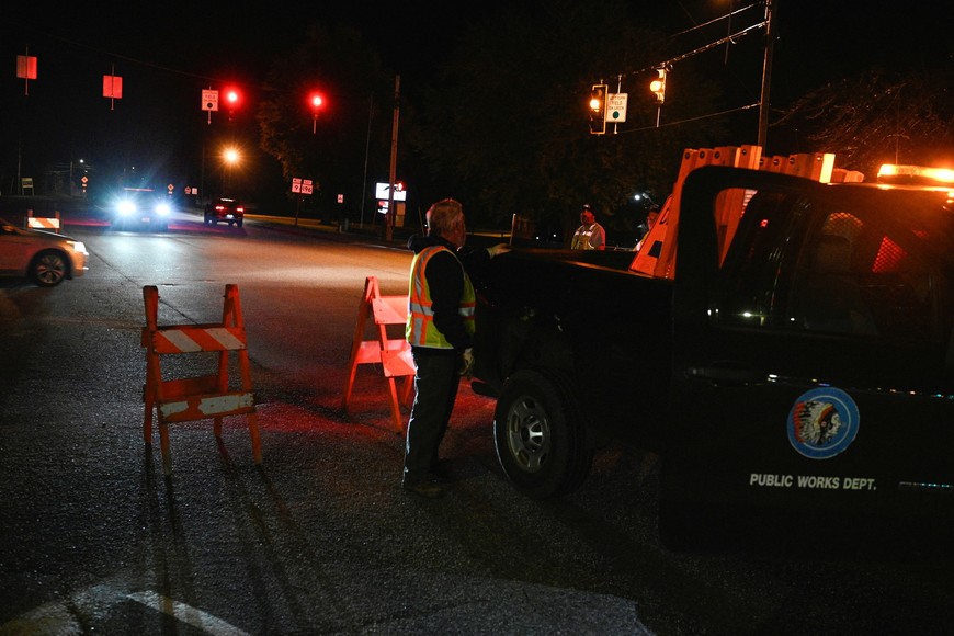 Workers set down detour signs while police organize around Lisbon High School as an active search for a gunman is underway after deadly mass shootings in Lewiston, Maine, U.S. October 26, 2023.  REUTERS/Nicholas Pfosi
