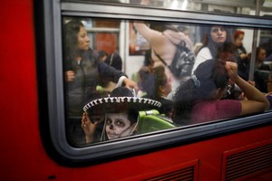 A boy with his face painted as the popular Mexican figure "Catrina" travels on a subway during the Day of the Dead celebrations, in Mexico City, Mexico November 1, 2023. REUTERS/Raquel Cunha
