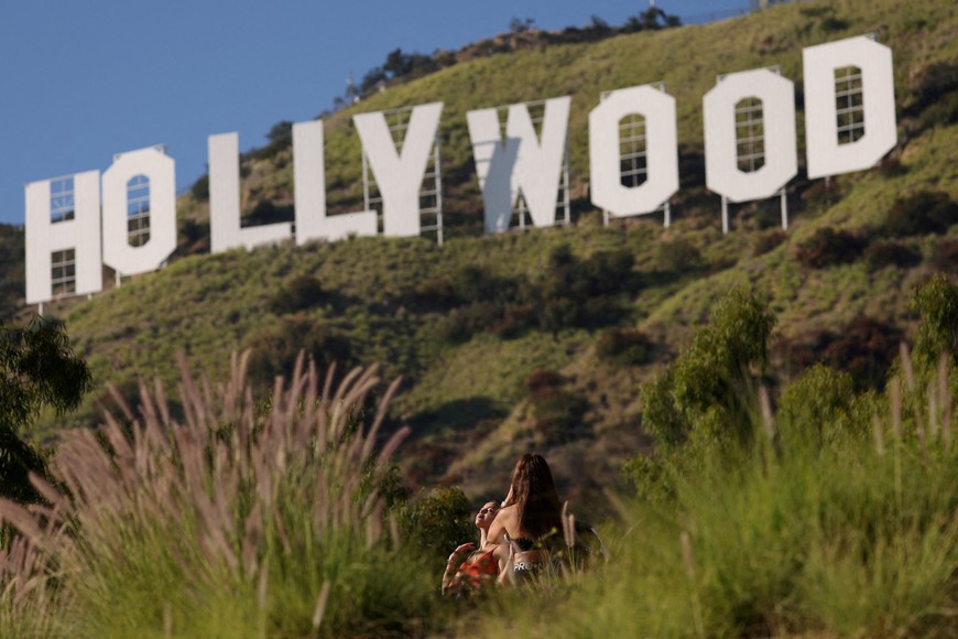 A woman poses by the iconic Hollywood sign on the day members of the Writers Guild of America (WGA) approved a new three-year contract with major studios, in Los Angeles, California, U.S., October 9, 2023. REUTERS/Mario Anzuoni     TPX IMAGES OF THE DAY