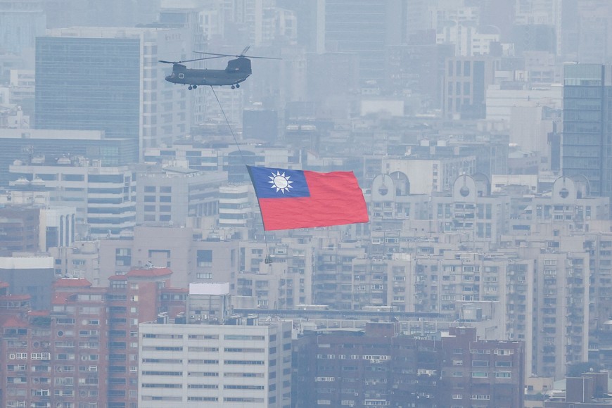 A Chinook helicopter carrying a Taiwan flag flies over the city during the country's National Day celebration in Taipei, Taiwan October 10, 2022. REUTERS/Carlos Garcia Rawlins     TPX IMAGES OF THE DAY
