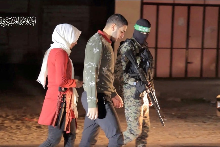 Hostages who were abducted by Hamas gunmen during the October 7 attack on Israel are handed over by Hamas militants to the International Red Cross, as part of a hostages-prisoners swap deal between Hamas and Israel amid a temporary truce, in an unknown location in the Gaza Strip, November 30, 2023. Hamas Military Wing/Handout via REUTERS THIS IMAGE HAS BEEN SUPPLIED BY A THIRD PARTY