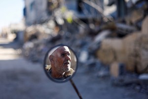 A man's face is reflected in a mirror, near the ruins of houses destroyed in Israeli strikes during the conflict, during a temporary truce between Hamas and Israel, in Khan Younis in the southern Gaza Strip, November 30, 2023. REUTERS/Mohammed Salem