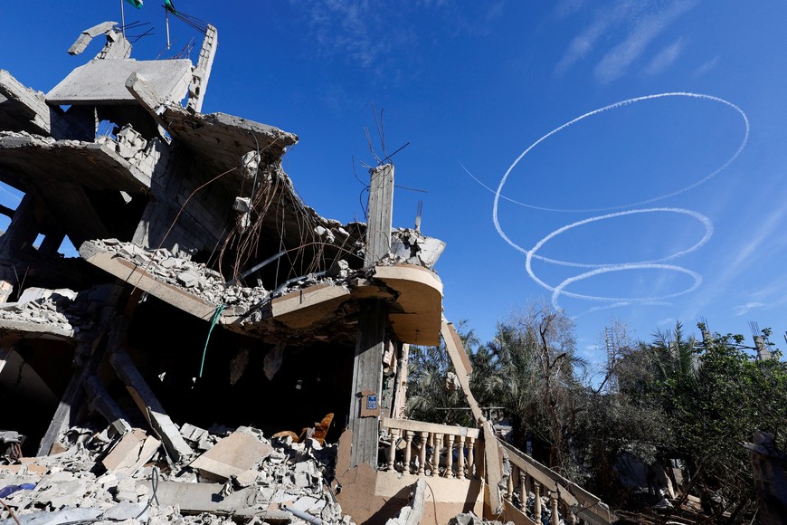 Israel aircrafts leave trails near the ruins of houses destroyed in Israeli strikes during the conflict, during a temporary truce between Hamas and Israel, in Khan Younis in the southern Gaza Strip, November 30, 2023. REUTERS/Mohammed Salem