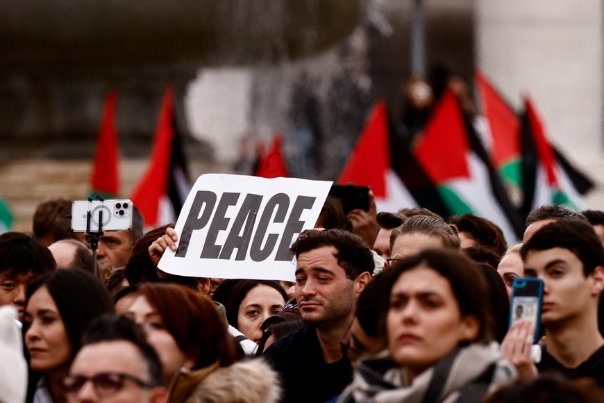 A placard and Palestinian flags are held as people gather to hear the traditional Christmas Day Urbi et Orbi message to the city and the world delivered by Pope Francis from the main balcony of St. Peter's Basilica at the Vatican, December 25, 2023. REUTERS/Yara Nardi