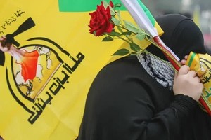 Una simpatizante de Hezbolá porta una bandera con los colores verde y amarillo del grupo, que posee una amplia popularidad en Líbano. Ahmad Al Rubaye / DW