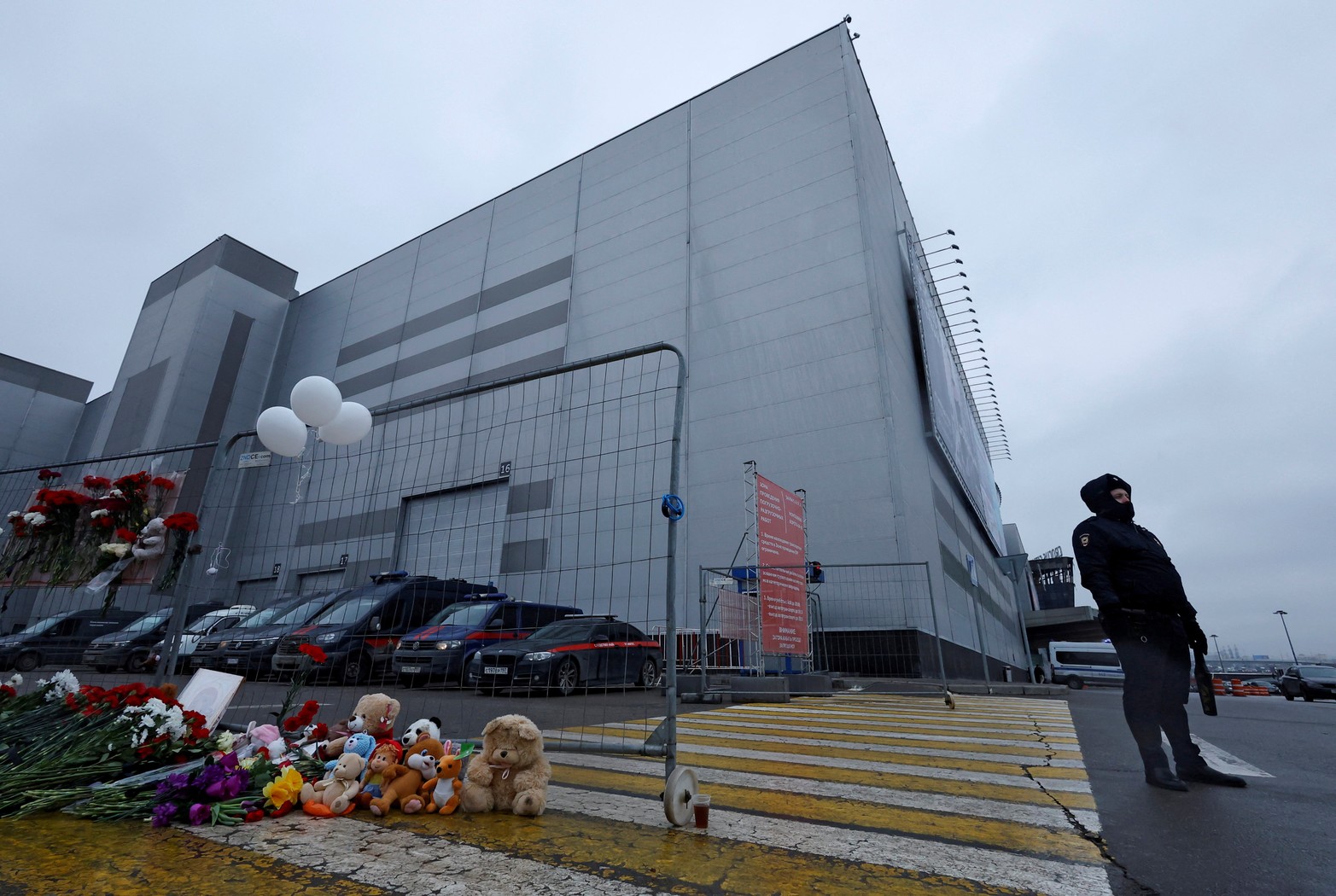 Un oficial de policía se encuentra junto a un monumento improvisado a las víctimas de un ataque a tiros en la sala de conciertos Crocus City Hall en la región de Moscú, Rusia.