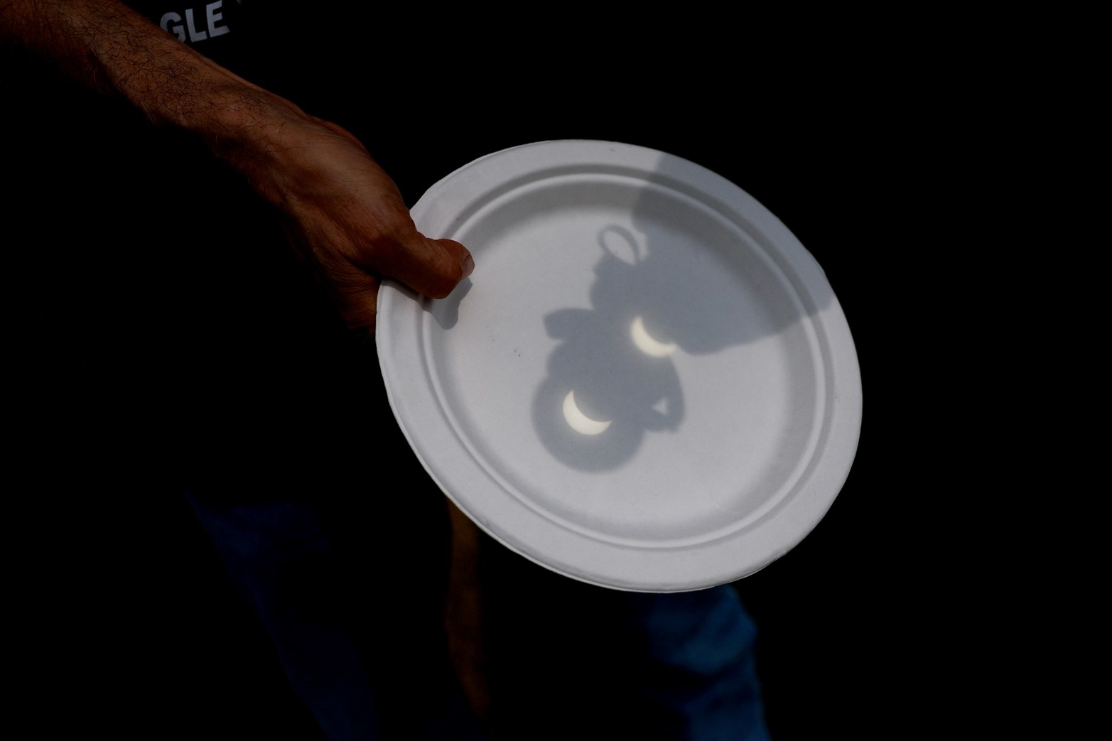 Una persona sostiene un plato durante el eclipse solar, donde la luna borra el sol, en Eagle Pass, Texas.