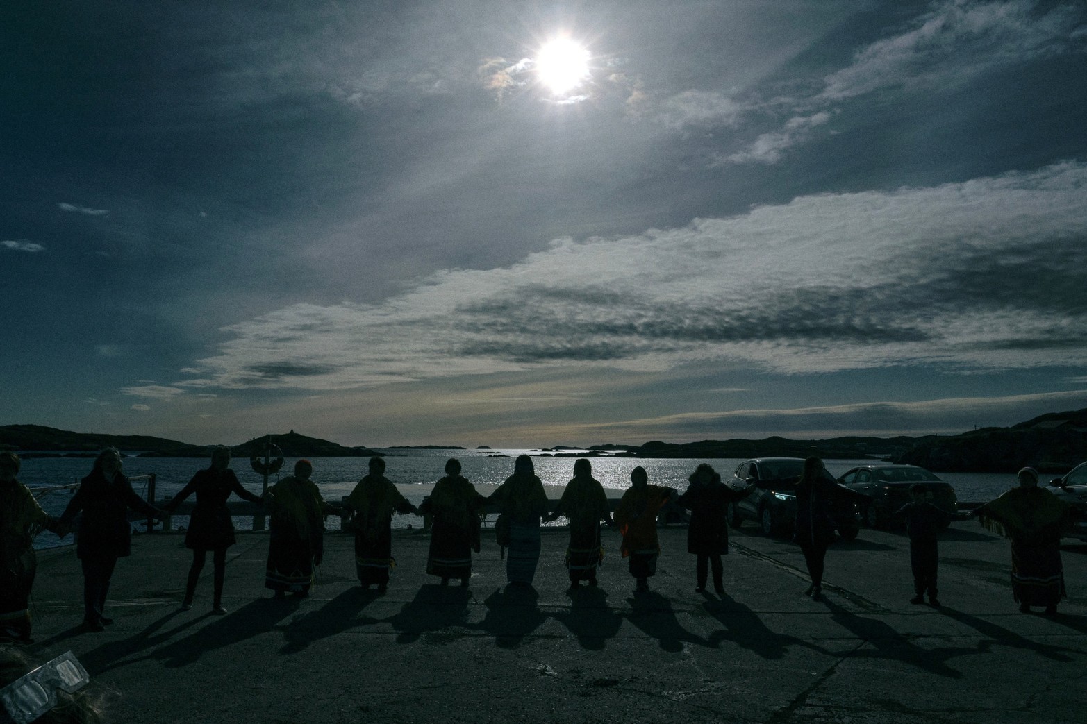 Los residentes asisten a una ceremonia durante un eclipse solar total, con la Isla Eclipse vista al fondo, en Burgeo, Terranova, Canadá.