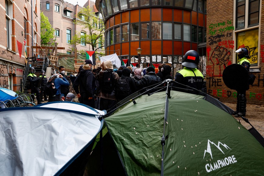 Police officers stand near tents next to pro-Palestinian protesters outside the University of Amsterdam during a protest against the ongoing conflict between Israel and the Palestinian Islamist group Hamas in Gaza, in Amsterdam, Netherlands, May 8 2024. REUTERS/Piroschka van de Wouw