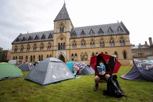 A local activist reads near tents at Oxford University, outside Oxford University Museum of Natural History, as students occupy parts of British university campuses to protest in support of Palestinians in Gaza, amidst the ongoing conflict between Israel and the Palestinian Islamist group Hamas, in Oxford, Britain, May 6, 2024. REUTERS/Hollie Adams