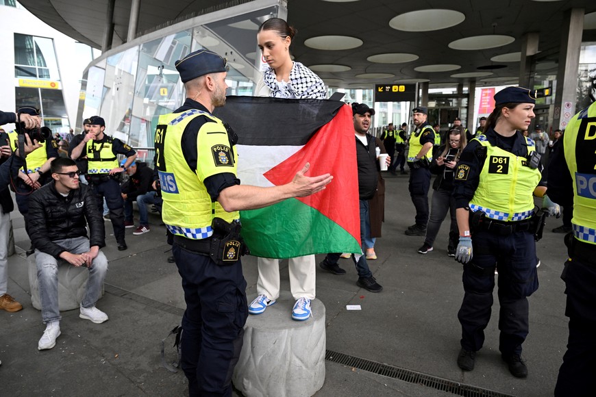 A protester holding a Palestinian flag stands in front of a police officer on the day of the "Stop Israel" demonstration, against Israel's participation in the Eurovision Song Contest due to its ongoing offensive in Gaza against Hamas, in Malmo, Sweden, May 11, 2024. TT News Agency/Jessica Gow via REUTERS      ATTENTION EDITORS - THIS IMAGE WAS PROVIDED BY A THIRD PARTY. SWEDEN OUT. NO COMMERCIAL OR EDITORIAL SALES IN SWEDEN.