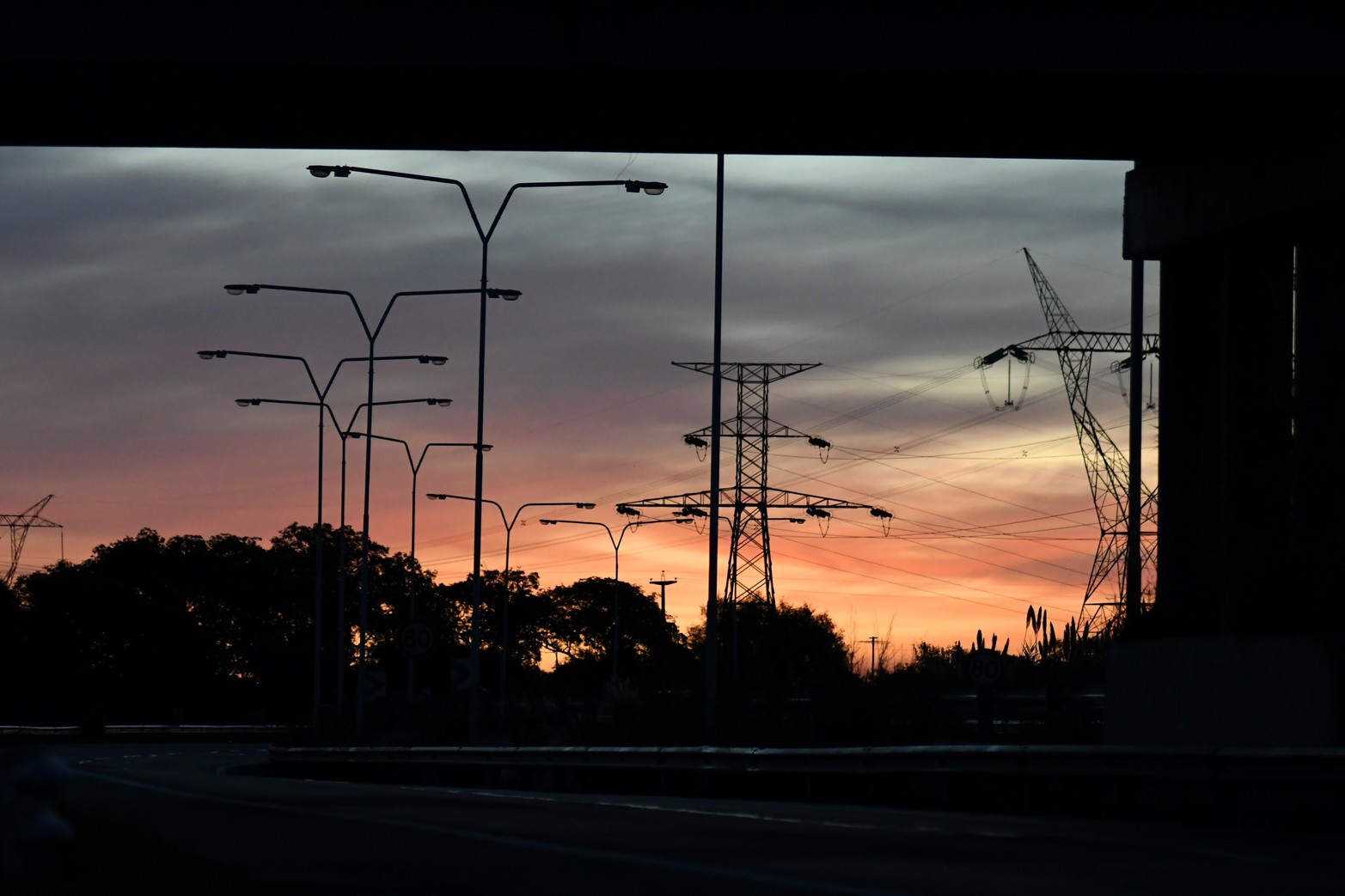 El contraluz. La ruta 168 a oscuras y la penumbra del atardecer deja ver las siluetas de las columnas de iluminación con los focos apagados. 