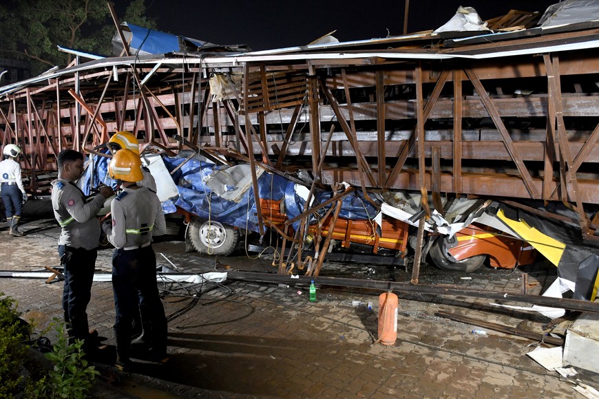 Firefighters stand next to the damaged vehicles trapped in the debris after a massive billboard fell during a rainstorm in Mumbai, India, May 13, 2024. REUTERS/Stringer