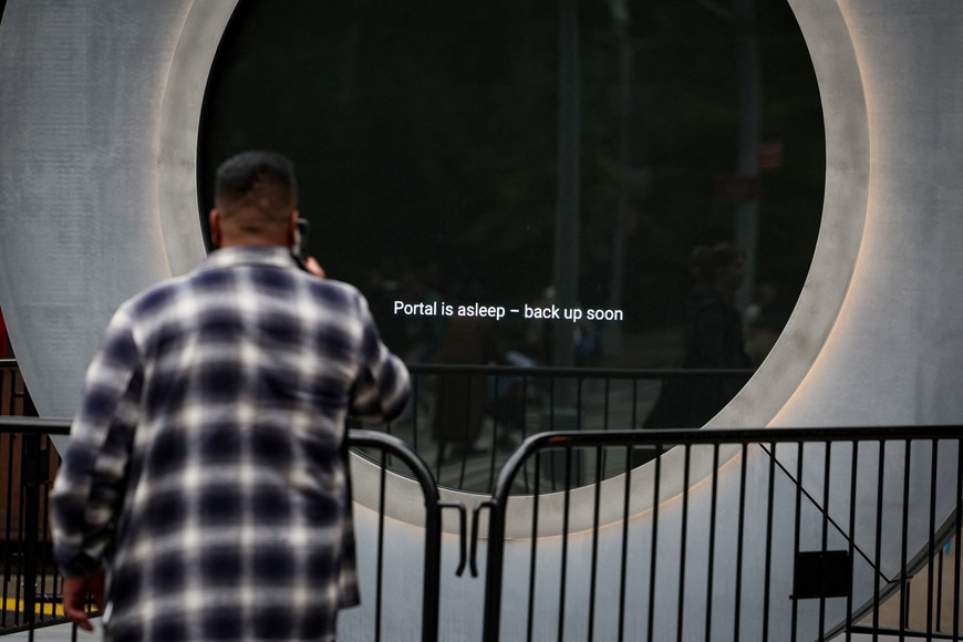 A man takes a photo of a message that is displayed on The Portal, a public technology sculpture that links with direct connection between Dublin, Ireland and the Flatiron district in Manhattan, after it had been temporarily disabled due inappropriate behavior, in New York City, U.S., May 15, 2024.  REUTERS/Brendan McDermid