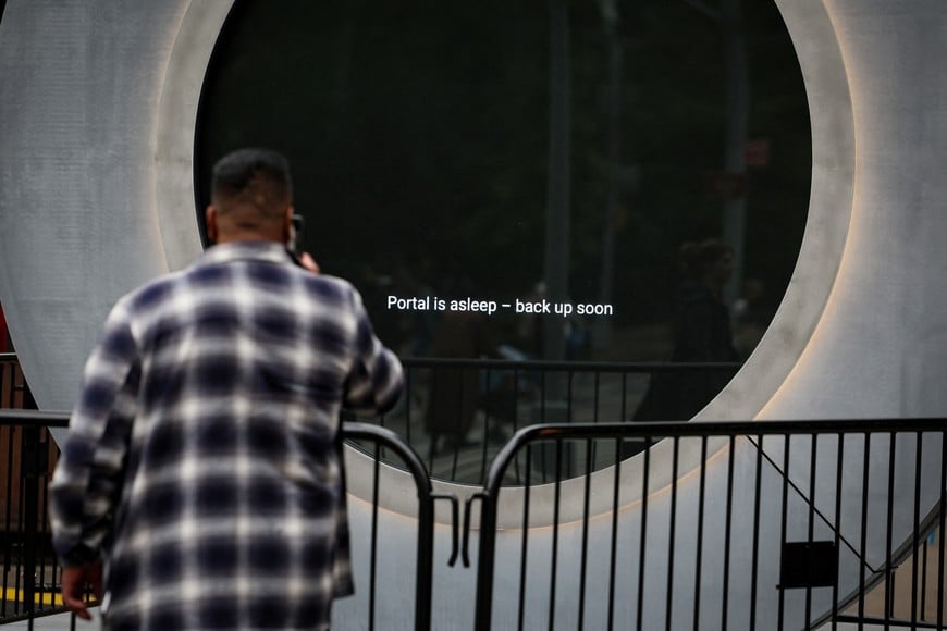 A man takes a photo of a message that is displayed on The Portal, a public technology sculpture that links with direct connection between Dublin, Ireland and the Flatiron district in Manhattan, after it had been temporarily disabled due inappropriate behavior, in New York City, U.S., May 15, 2024.  REUTERS/Brendan McDermid