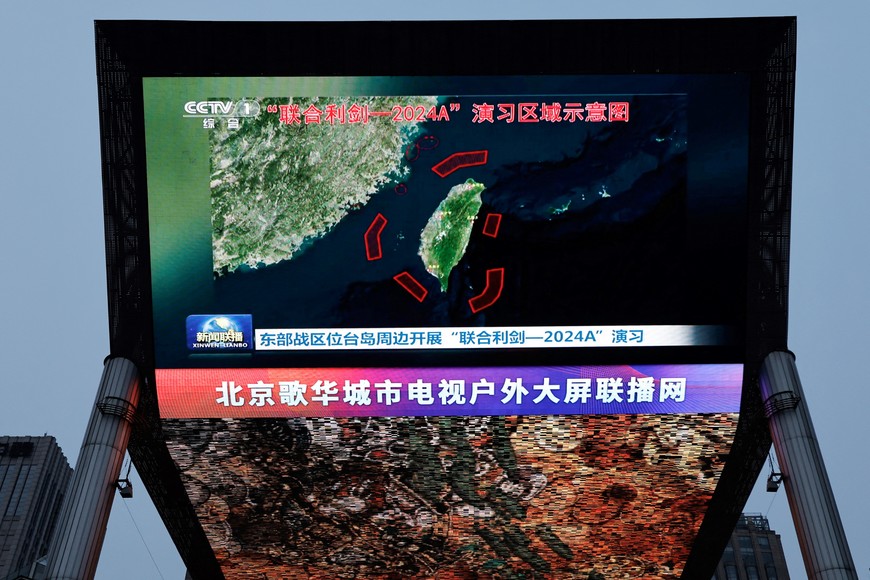 A large screen shows news footage of a map of military drills conducted by the Eastern Theatre Command of the Chinese People's Liberation Army (PLA) in five areas around the island of Taiwan, in Beijing, China May 23, 2024. REUTERS/Tingshu Wang