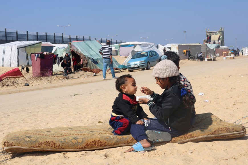 Displaced Palestinian girl, who fled her house due to Israeli strikes, feeds her brother at a tent camp, near the border with Egypt, in Rafah in the southern Gaza Strip, February 25, 2024. REUTERS/Saleh Salem      TPX IMAGES OF THE DAY