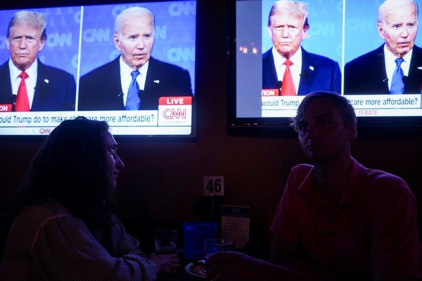 Republican presidential candidate, former U.S. President Donald Trump and Democrat presidential candidate, U.S. President Joe Biden are seen on television as people attend a watch party for the first U.S. presidential debate hosted by CNN in Atlanta, at Union Pub on Capitol Hill in Washington, U.S., June 27, 2024. REUTERS/Nathan Howard