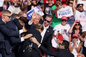 El candidato presidencial republicano y expresidente de Estados Unidos, Donald Trump, hace un gesto con el rostro ensangrentado mientras es asistido por personal del Servicio Secreto. Créditos: Reuters
