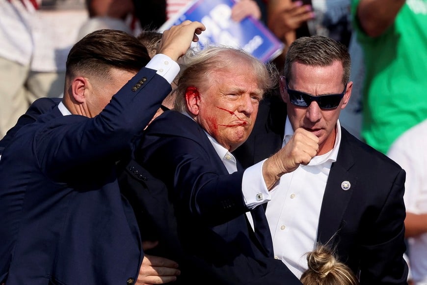 Republican presidential candidate and former U.S. President Donald Trump gestures as he is assisted by security personnel after gunfire rang out during a campaign rally at the Butler Farm Show in Butler, Pennsylvania, U.S., July 13, 2024. REUTERS/Brendan McDermid