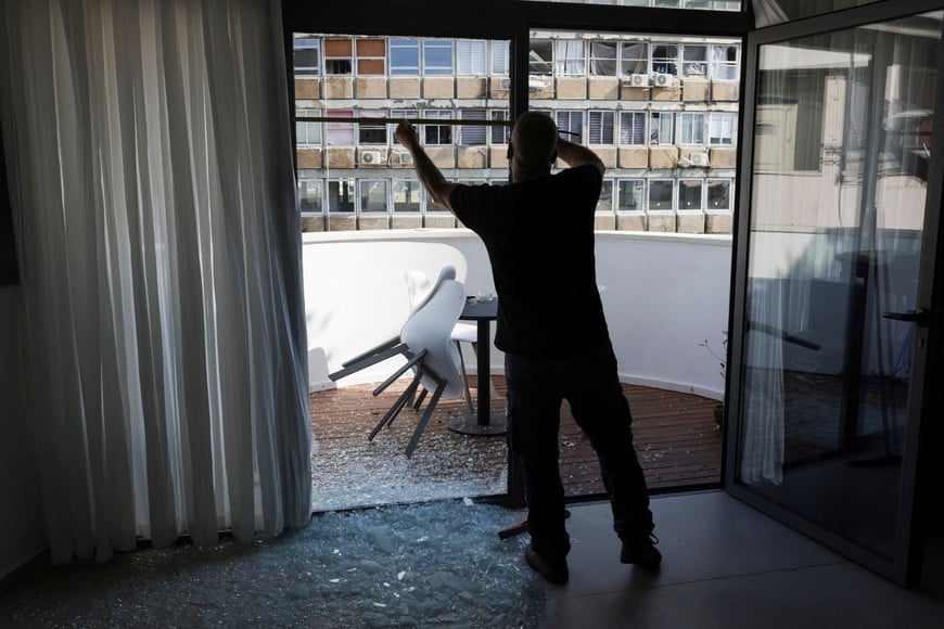 A worker measures a window damaged at a building near the site of an explosion, amid the Israel-Hamas conflict in Tel Aviv, Israel July 19, 2024. REUTERS/Ricardo Moraes