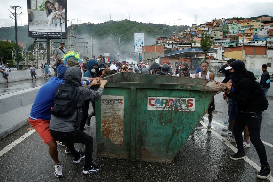 Supporters of Venezuelan opposition move a trash container during a protest following the announcement by the National Electoral Council that Venezuela's President Nicolas Maduro won the presidential election, in Caracas, Venezuela July 29, 2024. REUTERS/Leonardo Fernandez Viloria