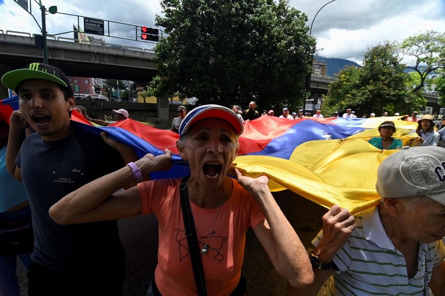 A woman shouts while holding a Venezuela's flag to protest election results that awarded Venezuela's President Nicolas Maduro with a third term, in Caracas, Venezuela July 30, 2024. REUTERS/Maxwell Briceno