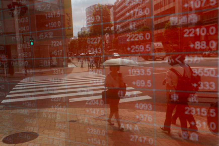 FILE PHOTO: A woman is reflected on an electronic stock quotation board outside a brokerage in Tokyo, Japan, August 6, 2024. REUTERS/Willy Kurniawan/File Photo