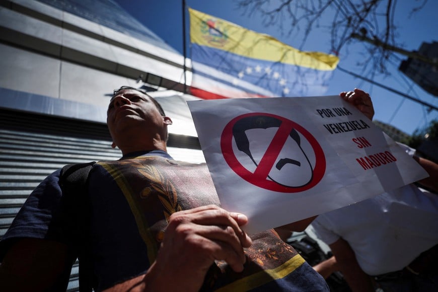 A Venezuelan resident in Argentina holds a placard depicting Venezuela's President Nicolas Maduro that reads "For a Venezuela without Maduro", as he protests outside the Venezuelan embassy to demand the opening of the electoral registry abroad, and the registration of candidates for the presidential elections which closes today, amidst uncertainty as to who will carry the banner of the country's opposition coalition, in Buenos Aires, Argentina March 25, 2024. REUTERS/Agustin Marcarian