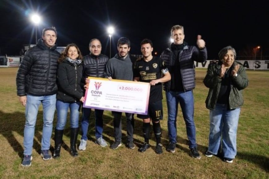 El presidente de la Liga Venadense, Jorge Bournot; el intendente Leonel Chiarella; la senadora provincial Leticia Di Gregorio; el diputado provincial Leo Calaianov; el concejal Carlos Jordán; y la Secretaria de Territorialidad, Miriam Carabajal; posando junto con el capitán del Pulga Rodrigo Aglieri. Foto: Fabián Gallego.