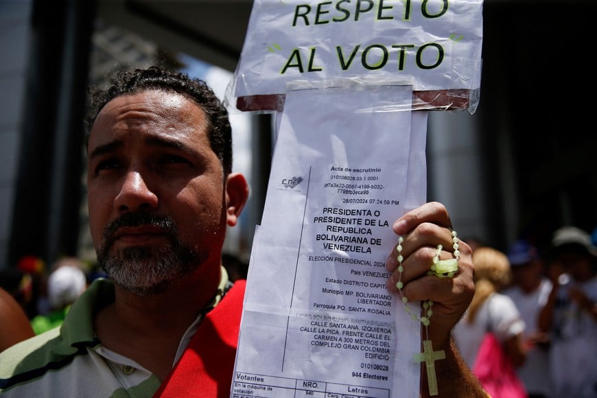 A man holds a copy of electoral records and a rosary, as supporters gather on the day of a march called by Venezuela's opposition leader Maria Corina Machado, amid the disputed presidential election, in Caracas, Venezuela, August 17, 2024. REUTERS/Leonardo Fernandez Viloria