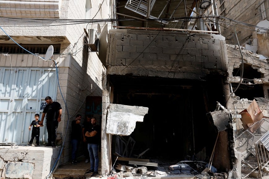 Palestinians stand near a damaged house following an Israeli military raid in Tulkarm in the Israeli-occupied West Bank, August 29, 2024. REUTERS/Mohammed Torokman