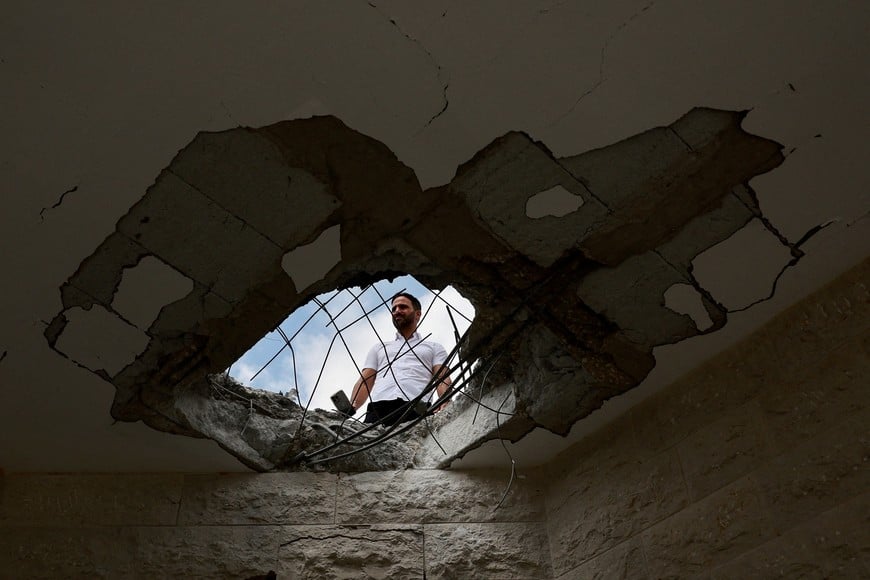 An official property surveyor assesses the damage to a residential building following a direct-hit from a projectile, after Hezbollah launched hundreds of rockets and drones towards Israel in what the Iranian-backed movement said was a response to the assassination of a senior commander in Beirut last month, in northern Israel August 25, 2024. REUTERS/Ammar Awad     TPX IMAGES OF THE DAY