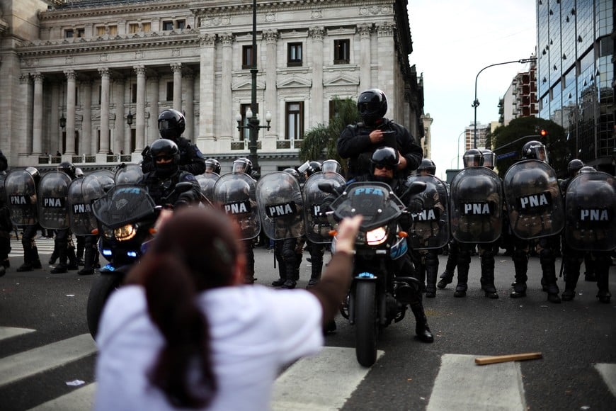 A woman reacts in front of police officers during a protest against Argentina's President Javier Milei's decision to veto a pension reform, outside the National Congress, in Buenos Aires, Argentina, September 11, 2024. REUTERS/Agustin Marcarian