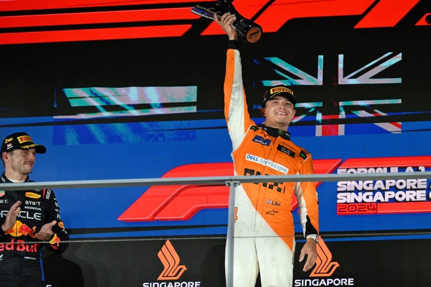 Formula One F1 - Singapore Grand Prix - Marina Bay Street Circuit, Singapore - September 22, 2024
McLaren's Lando Norris celebrates with a trophy on the podium after winning the Singapore Grand Prix alongside second placed Red Bull's Max Verstappen REUTERS/Caroline Chia