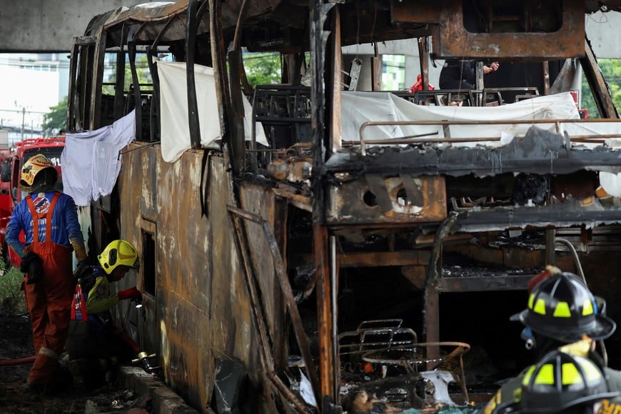 First responders inspect a burnt-out bus that caught fire while carrying teachers and students from Wat Khao Phraya school, reportedly resulting in fatalities and injuries, on the outskirts of Bangkok, Thailand, October 1, 2024. REUTERS/Chalinee Thirasupa