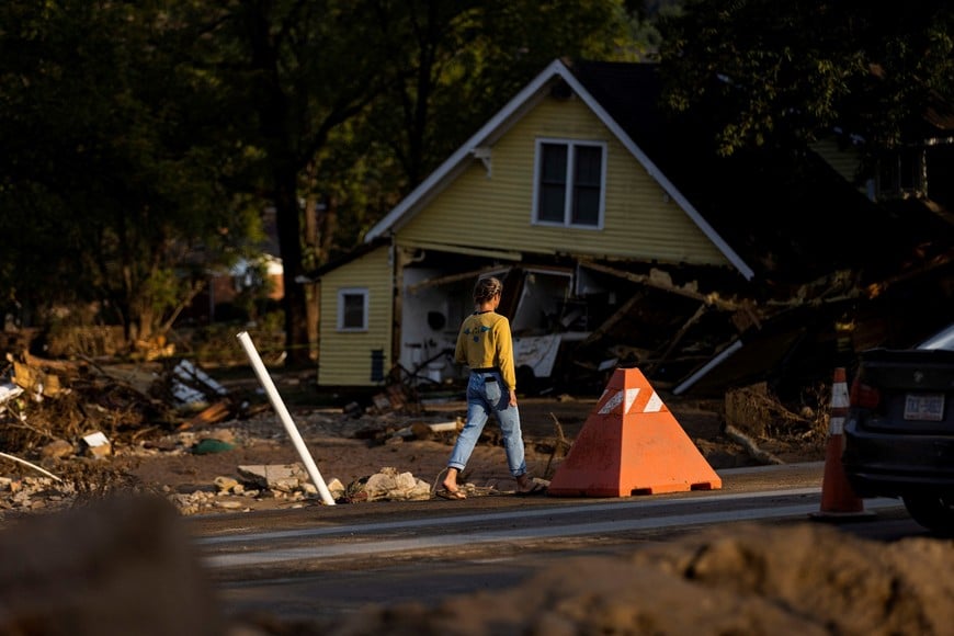 A woman walks by a zone affected by floods following the passing of Hurricane Helene, in Old Fort, North Carolina, U.S., October 4, 2024.  REUTERS/Eduardo Munoz