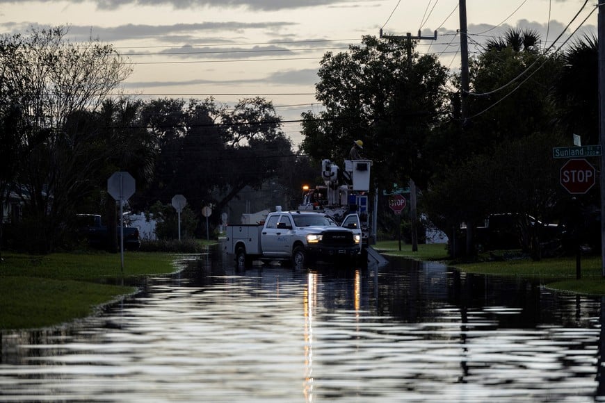 Utility workers repair a power line on a flooded street after Hurricane Milton made landfall in South Daytona, Florida, U.S., October 11, 2024. REUTERS/Ricardo Arduengo