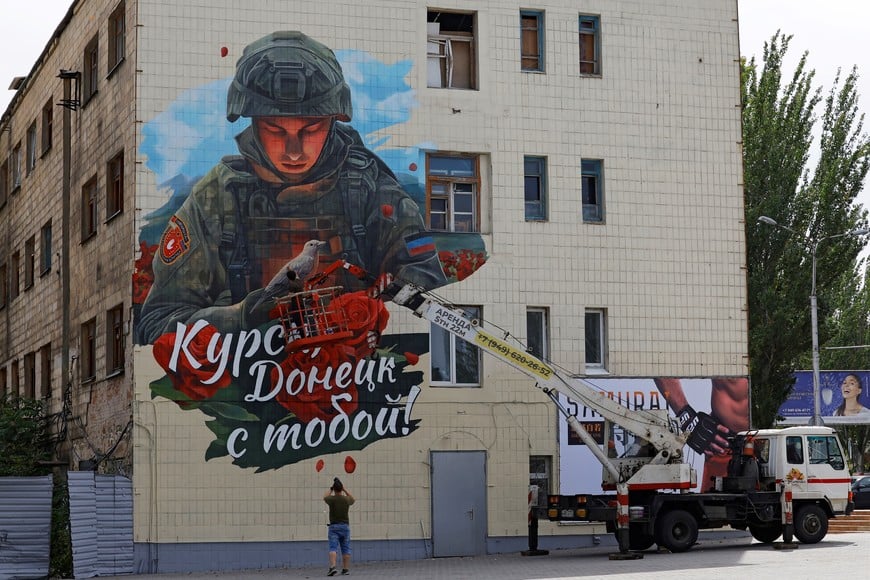 Painter Vladislav Stepnoi works on his mural reading "Kursk, Donetsk is with you!" in support of residents of Russia's Kursk Region in the course of Russia-Ukraine conflict, on the facade of a building in Donetsk, Russian-controlled Ukraine, August 31, 2024. REUTERS/Alexander Ermochenko