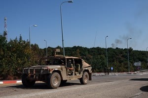 An Israeli military vehicle drives as smoke rises in the background after a missile strike, amid cross-border hostilities between Hezbollah and Israel, near Sasa, Israel, October 14, 2024. REUTERS/Gonzalo Fuentes