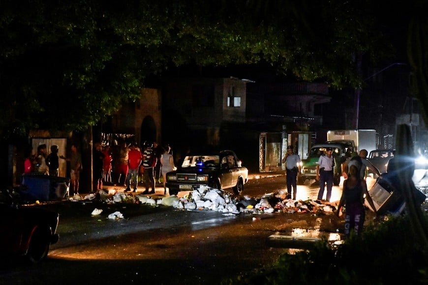 Cuban police stand next to debris used to block a street during a protest against a blackout, in Havana, Cuba October 19, 2024. REUTERS/Norlys Perez