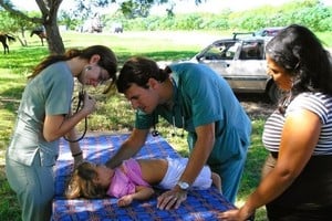 Jóvenes residentes de pediatría, atendiendo en una camilla improvisada, en un campamento de evacuados.