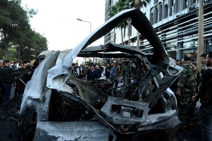 (241021) -- DAMASCO, 21 octubre, 2024 (Xinhua) -- Personas se reúnen alrededor de los restos de un vehículo alcanzado por un ataque aéreo israelí, en el barrio Mazzeh de Damasco, Siria, el 21 de octubre de 2024. Dos civiles murieron y otros tres resultaron heridos en un ataque aéreo israelí el lunes contra un vehículo civil en el oeste de la capital siria de Damasco, dijo el Ministerio de Defensa sirio. (Xinhua/Ammar Safarjalani) (rtg) (ah) (ce)