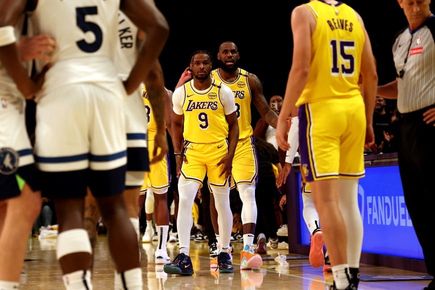 Oct 22, 2024; Los Angeles, California, USA; Los Angeles Lakers forward LeBron James (23) checks into the game with his son, guard Bronny James (9) during the second quarter against the Minnesota Timberwolves at Crypto.com Arena. This marked the first time in NBA history that a father and son played together. Mandatory Credit: Jason Parkhurst-Imagn Images