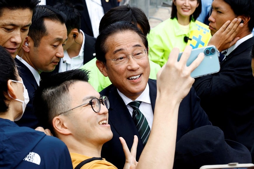 Fumio Kishida, Japan's former Prime Minister and a Liberal Democratic Party (LDP) candidate for the upcoming general election, takes a selfie with a man at a campaign to support a local candidate in Tokyo, Japan October 25, 2024. REUTERS/Kim Kyung-Hoon     TPX IMAGES OF THE DAY