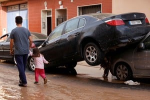 People walk on a street next to damaged cars after torrential rains caused flooding in Guadassuar, Valencia region, Spain, October 30, 2024. REUTERS/Eva Manez     TPX IMAGES OF THE DAY