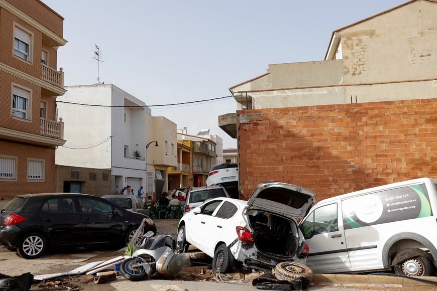 People gather next to damaged cars after torrential rains caused flooding in Guadassuar, Valencia region, Spain, October 30, 2024. REUTERS/Eva Manez