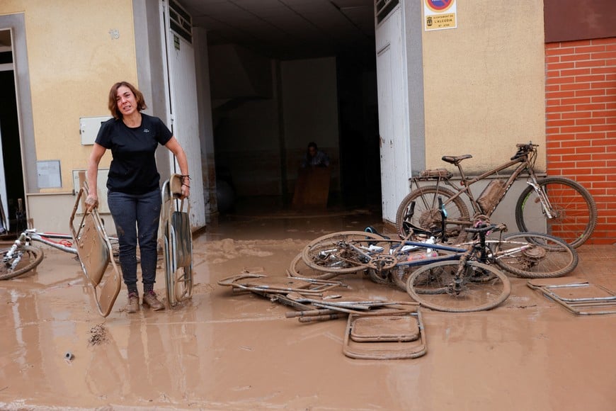 A woman carries out folding chairs caked in mud after torrential rains caused flooding in La Alcudia, Valencia region, Spain, October 30, 2024. REUTERS/Eva Manez     TPX IMAGES OF THE DAY