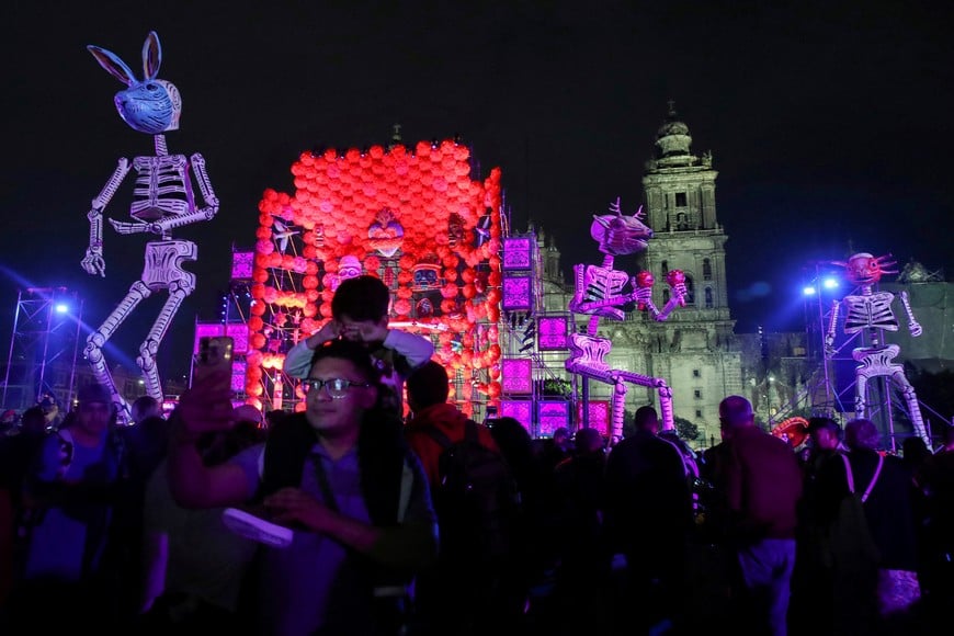 A man takes a selfie next to other people gathering near art installations of skeletons and other decorations, ahead of the Day of the Dead, as the Metropolitan Cathedral is seen in the background, at Zocalo Square in Mexico City, Mexico, October 30, 2024. REUTERS/Henry Romero