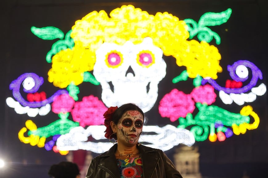 (241031) -- CIUDAD DE MEXICO, 31 octubre, 2024 (Xinhua) -- Imagen del 30 de octubre de 2024 de una mujer caracterizada como una catrina vista frente al alumbrado correspondiente a la Ofrenda Monumental y Alumbrado Decorativo alusivo al Día de Muertos, en el Zócalo de la Ciudad de México, capital de México. (Xinhua/Francisco Cañedo) (fc) (jg) (vf)